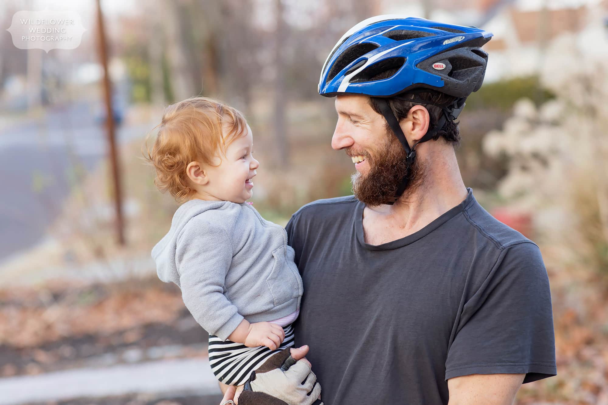 This outdoorsy family photography session with dad in bicycle helmet holding his baby.