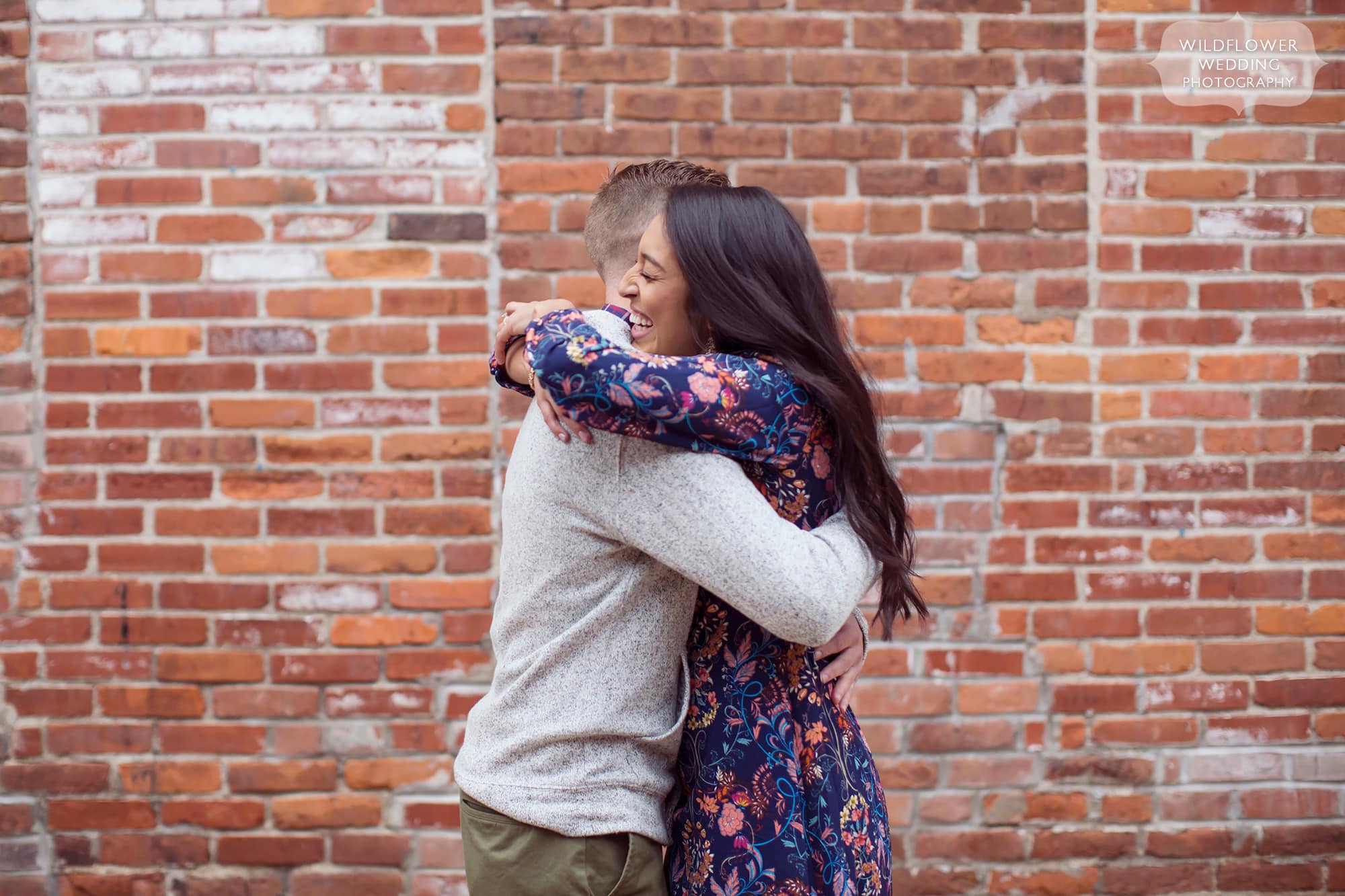 Natural photos of engaged couple with brick wall behind them in Columbia, MO near MU.