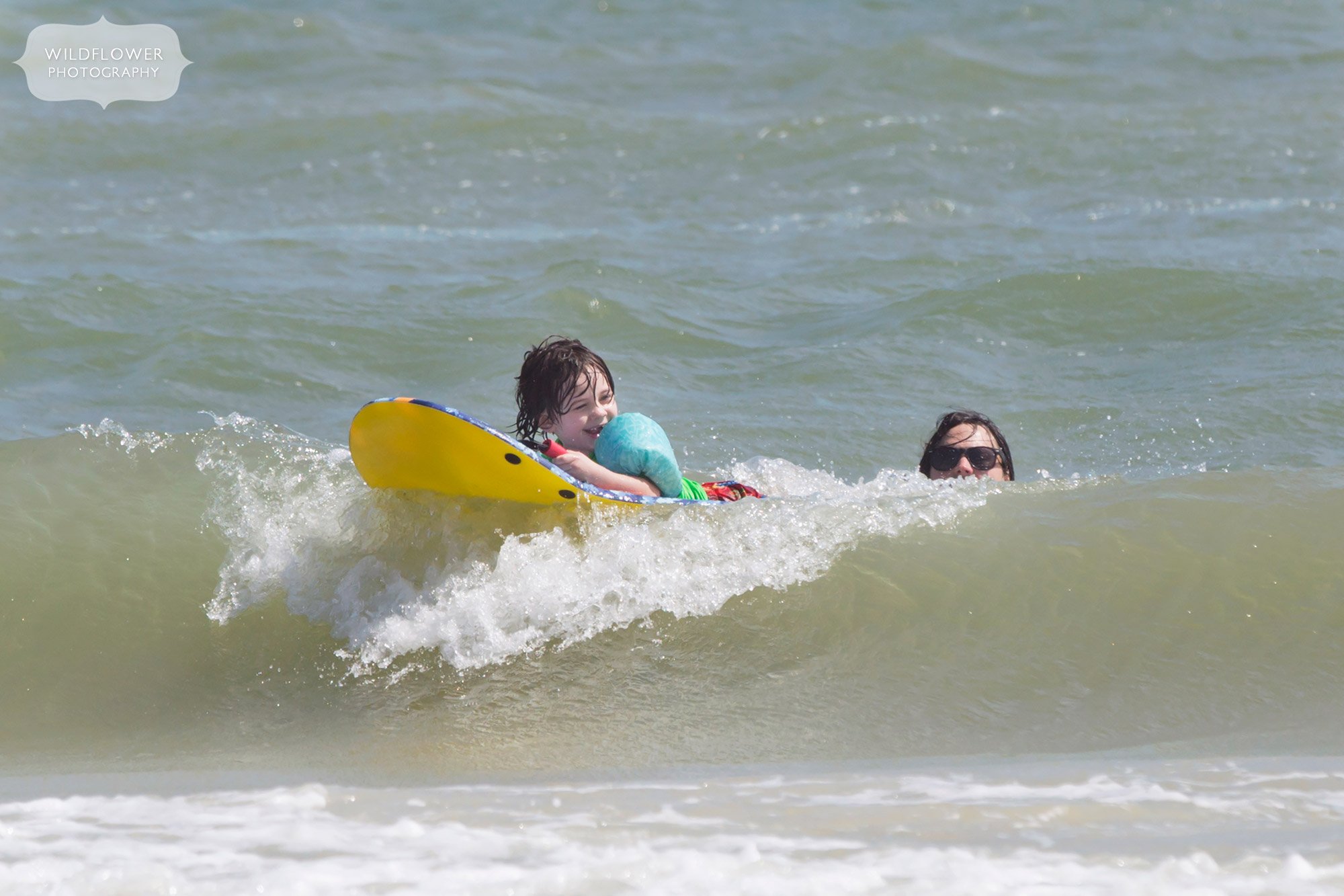 A boy smiling while boogie boarding on St. George Island in Florida.