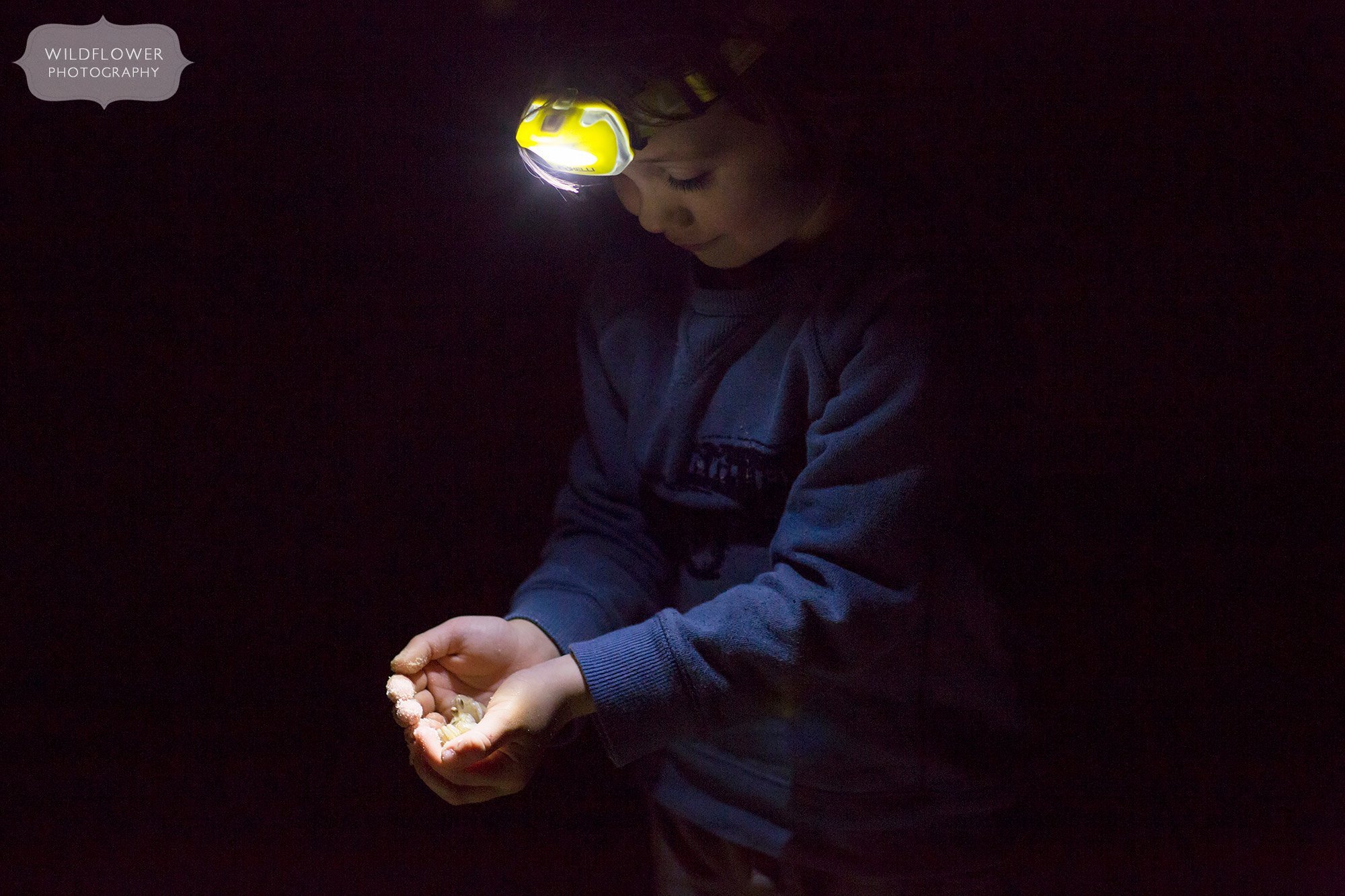 Boy holding a ghost crab with headlamp on St. George Island during beach vacation.