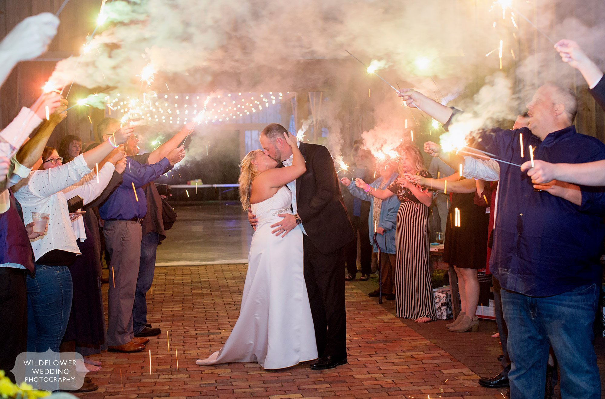 The bride and groom kiss under sparklers at the Schwinn Barn.