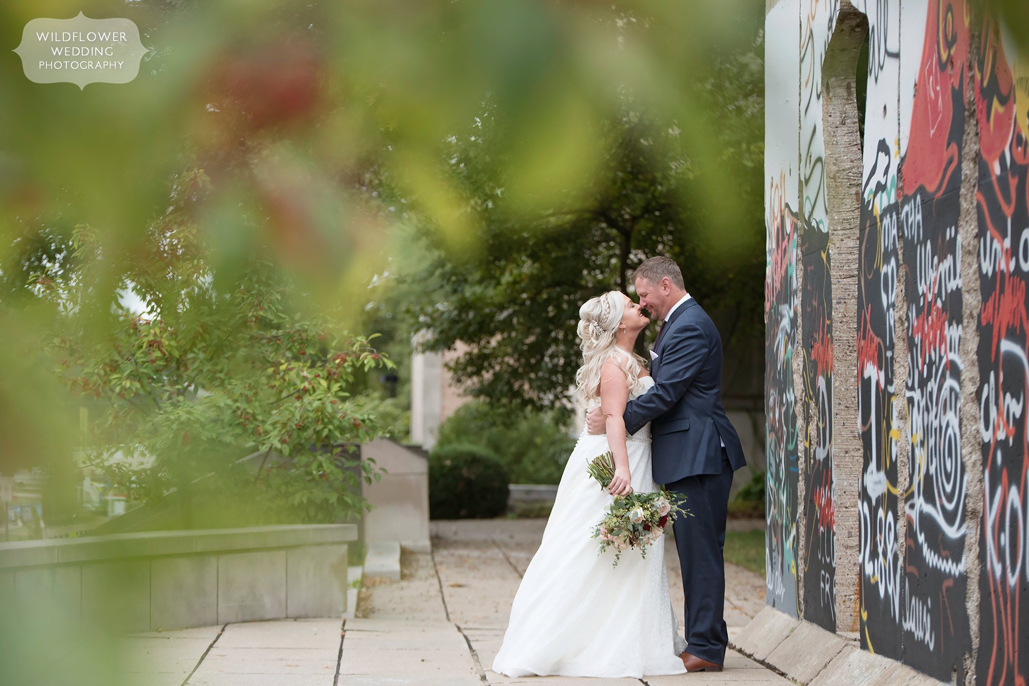 The bride and groom kiss outside before their Churchill Museum wedding by the Berlin Wall in Fulton, MO.