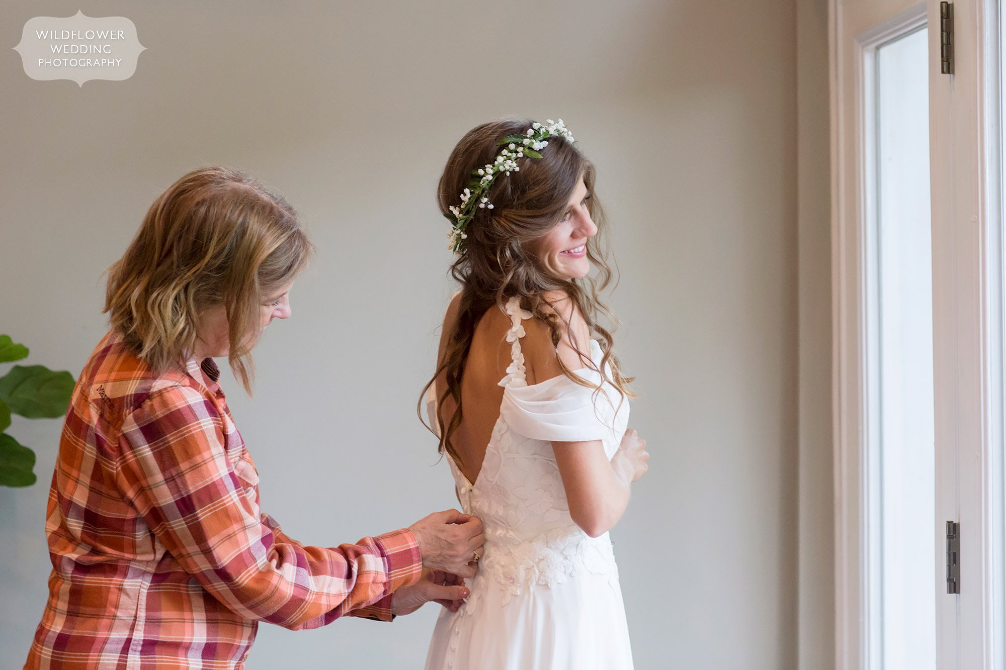 Great candid photographer captures bride's mom putting on dress at this Little Piney Lodge wedding.