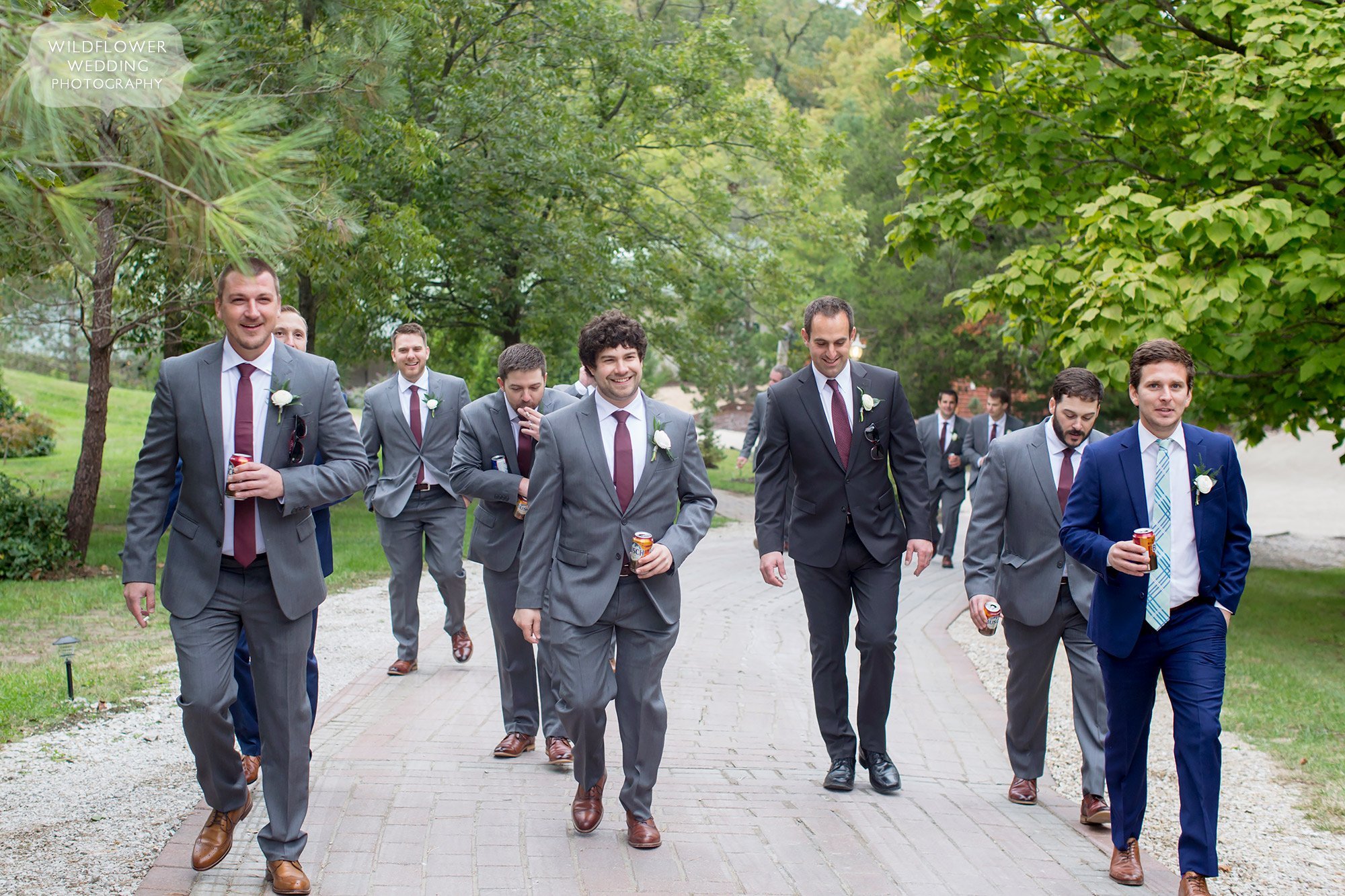 Groomsmen walk up the path at the outdoor Little Piney Lodge wedding venue.