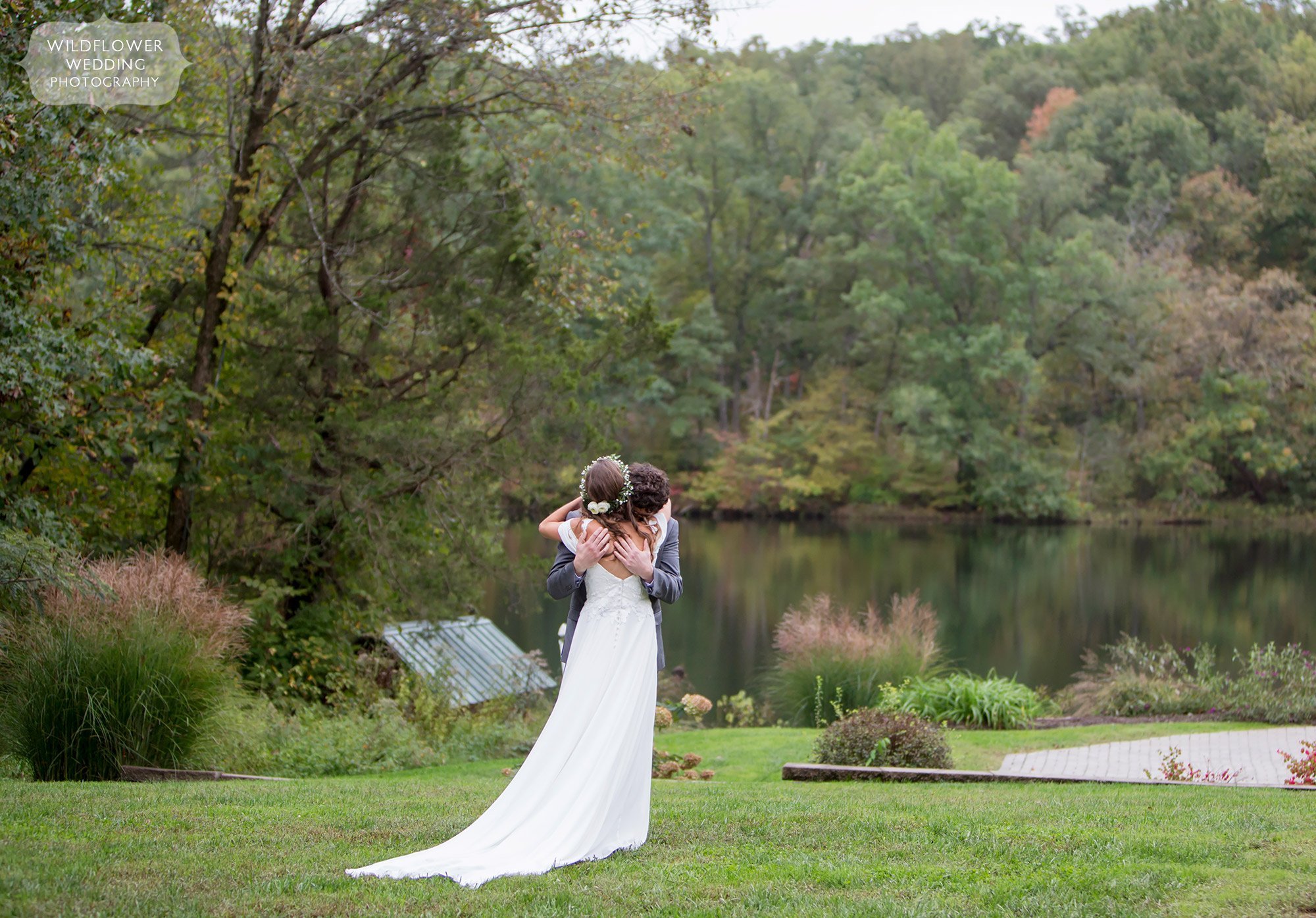 The bride and groom hug by the lake at the Little Piney Lodge wedding venue.