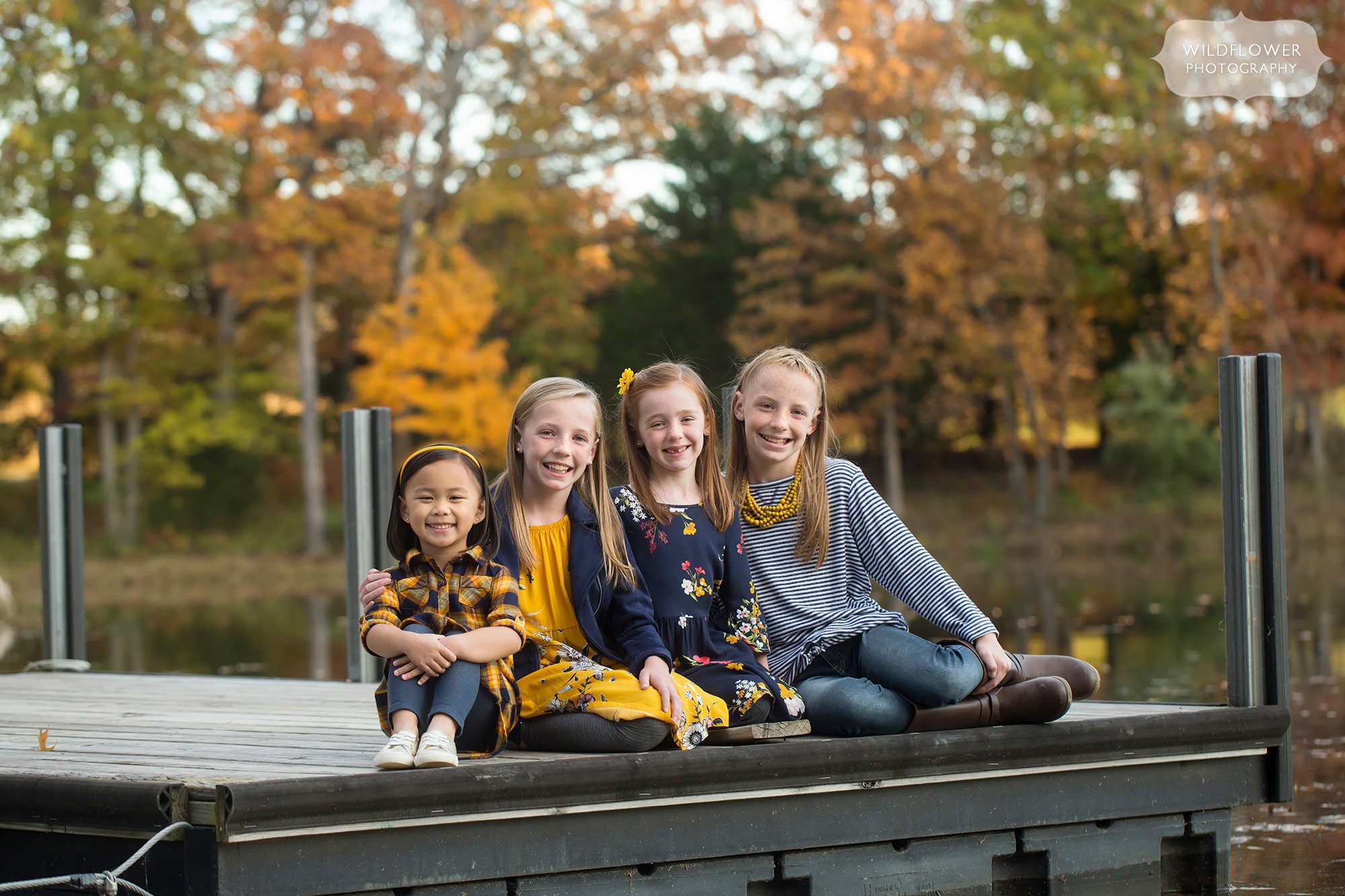 Sisters sit on a dock for this family photo session.