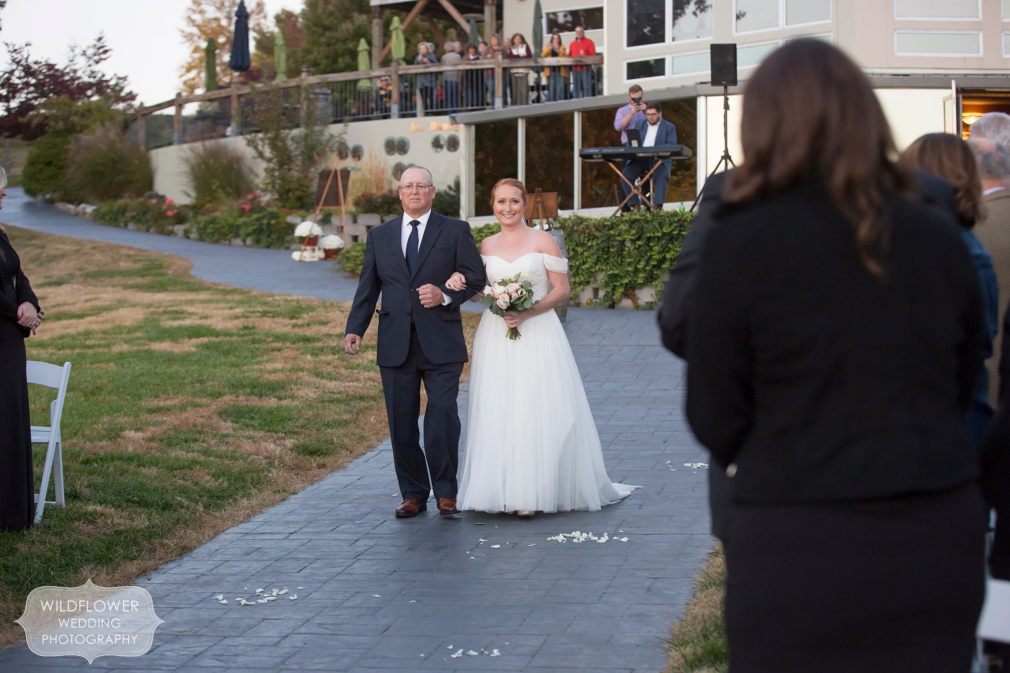 The bride and her father walk into the outdoor ceremony at Les Bourgeois Winery.