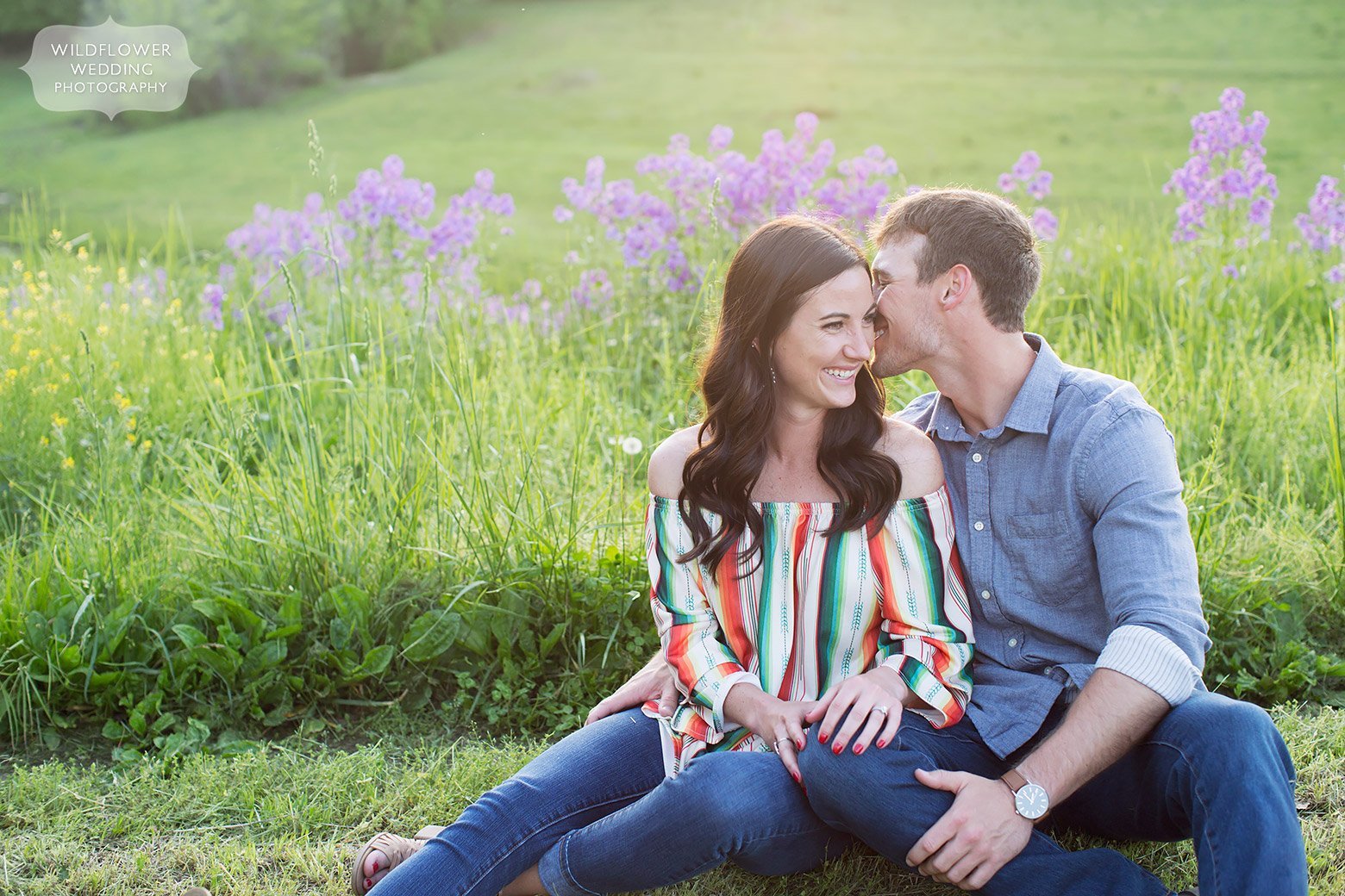The couple sits among purple wildflowers on their farm in mid-MO for an engagement photo shoot.