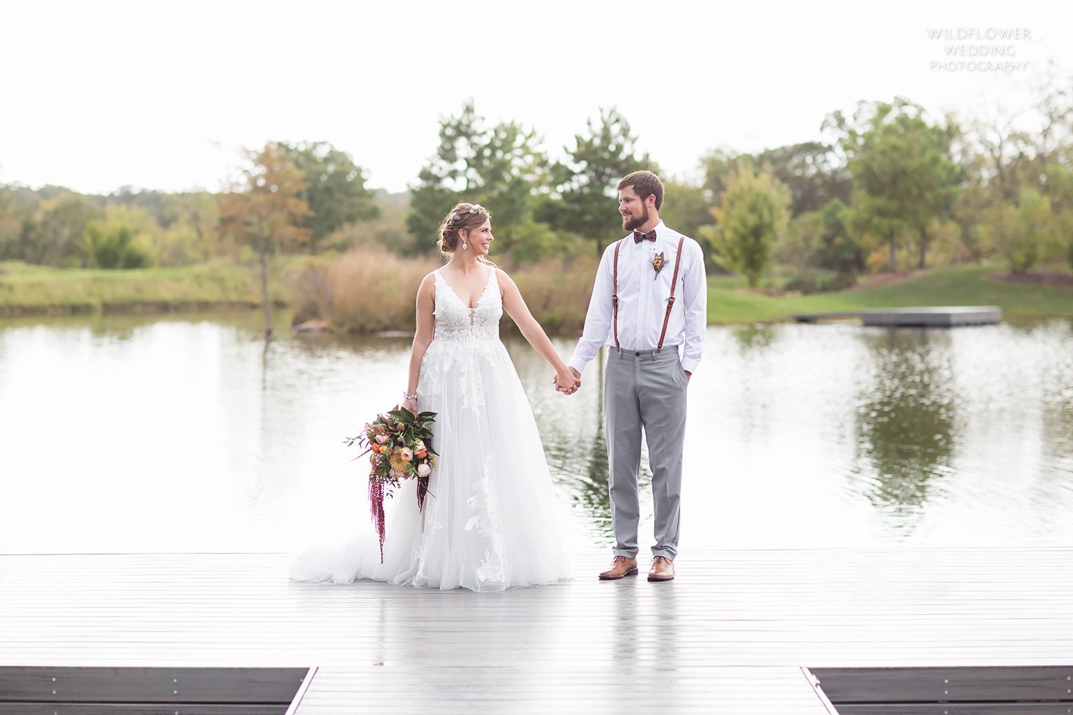 Bride and groom stand on edge of dock at October Hermann wedding in MO.