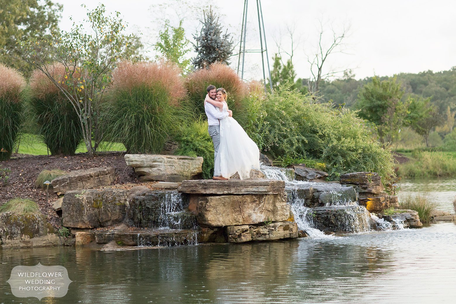 Bride and groom stand by waterfall in Hermann, MO.