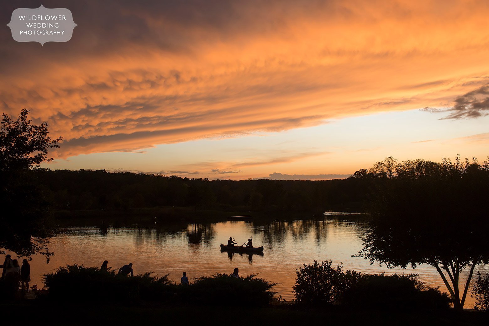 People canoeing under a pink sunset sky at Hermann MO wedding.