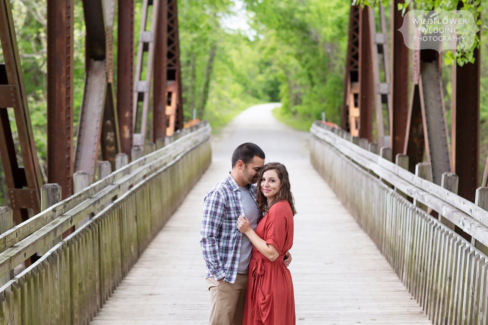 Couple stands on a rustic bridge 