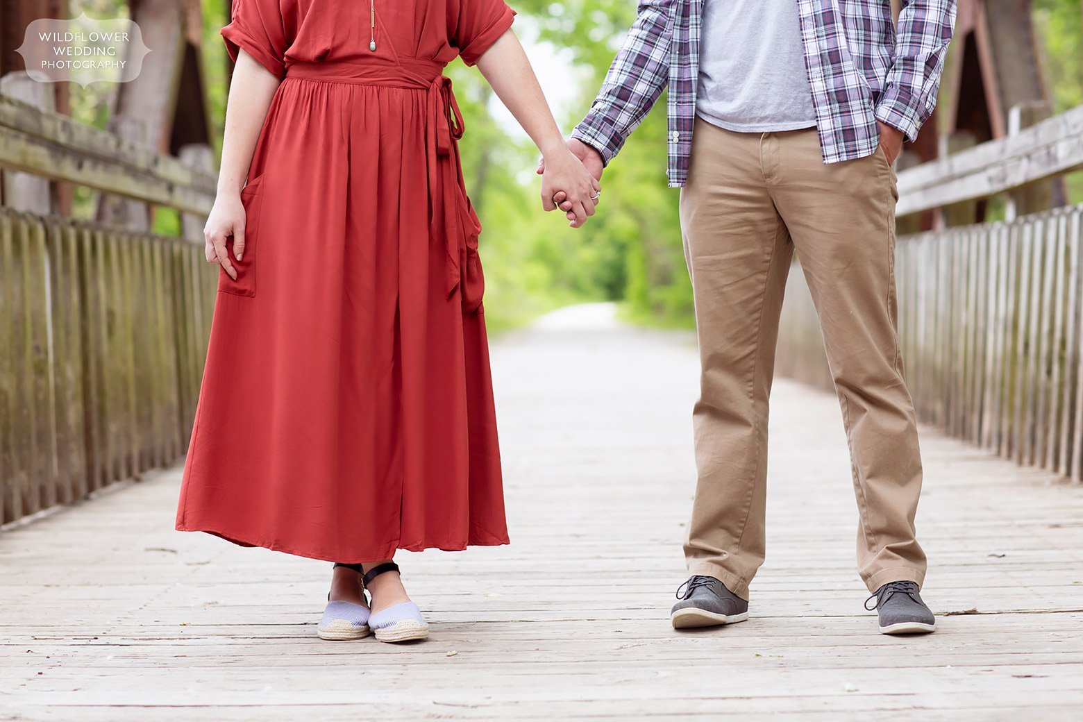 Girl in red dress and boy in plaid holding hands along bike path.
