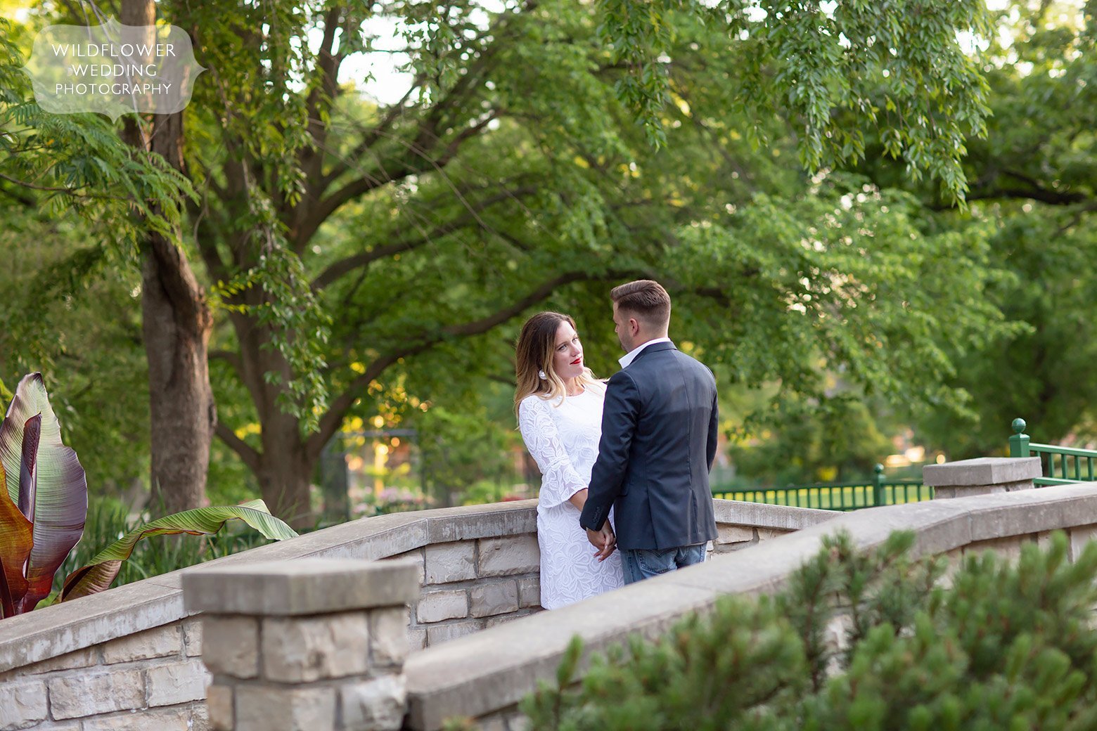 Couple stands on stone bridge at Shelter Gardens in Columbia, MO.