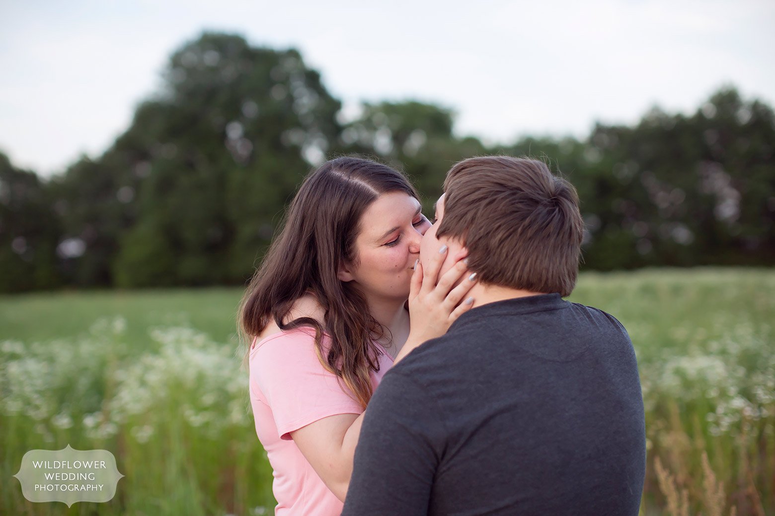 Girl pulls in boy for a kiss during Emerson Fields engagement photography session in mid-MO.