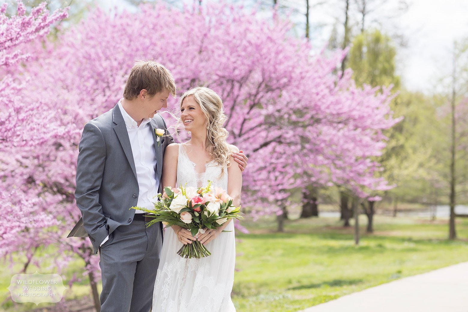 Bride and groom pose in front of rosebud trees in Forest Park for their spring wedding.