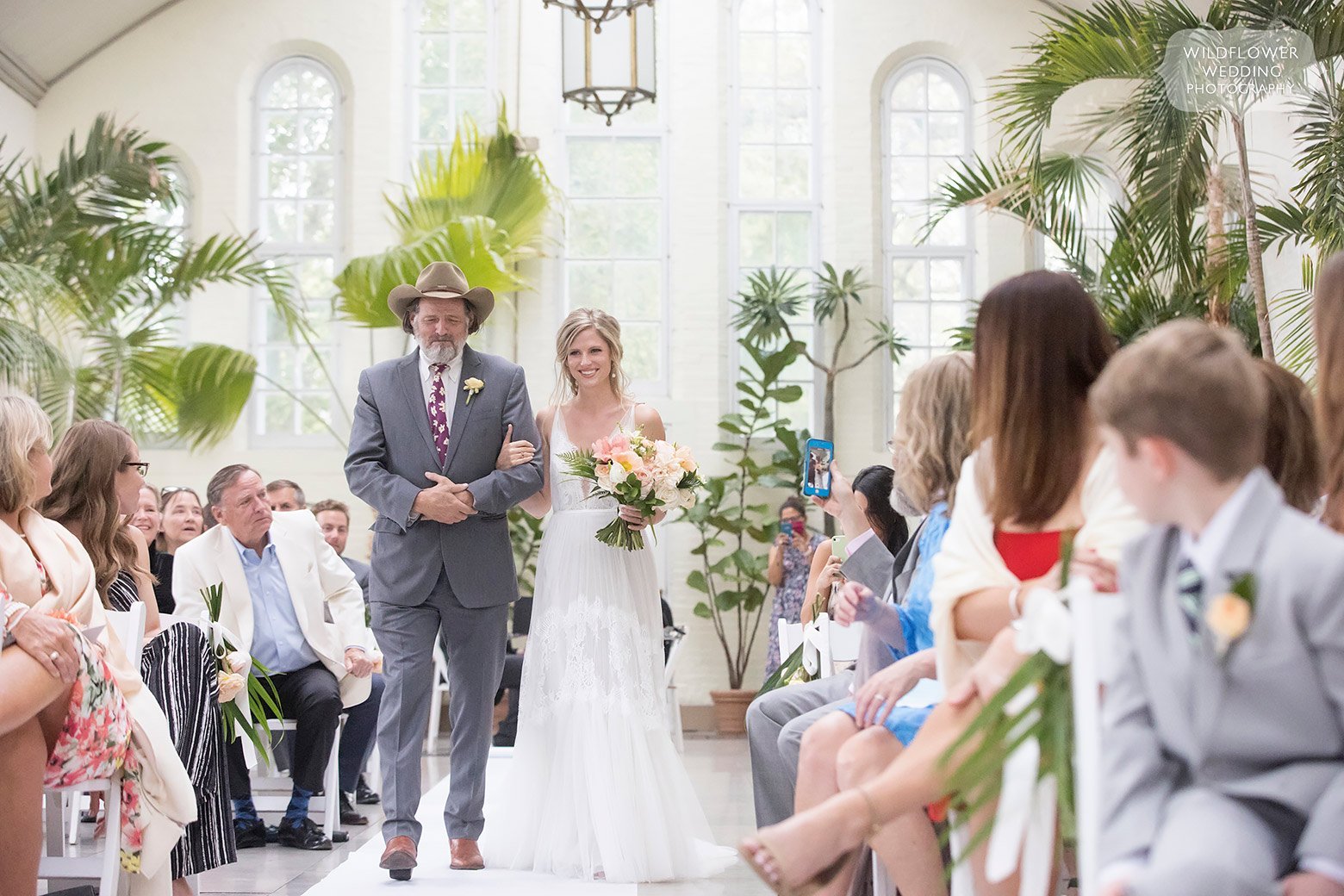Bride walks down aisle with dad at Piper Palm House wedding venue.
