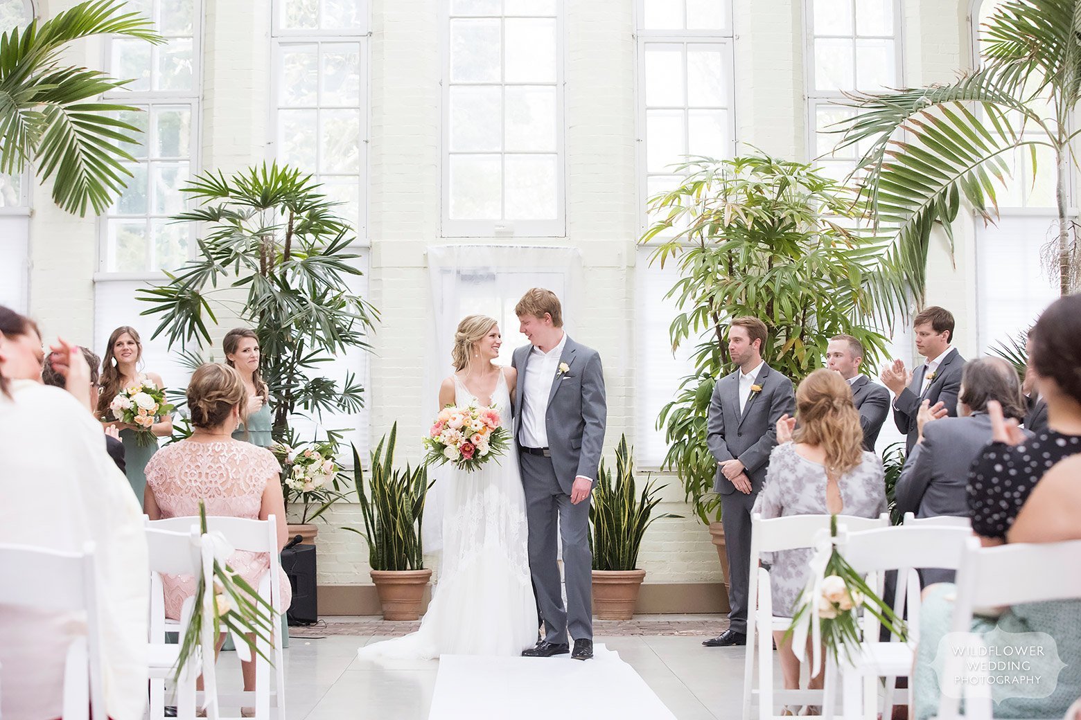 Bride and groom smile after ceremony at indoor greenhouse in St. Louis park.
