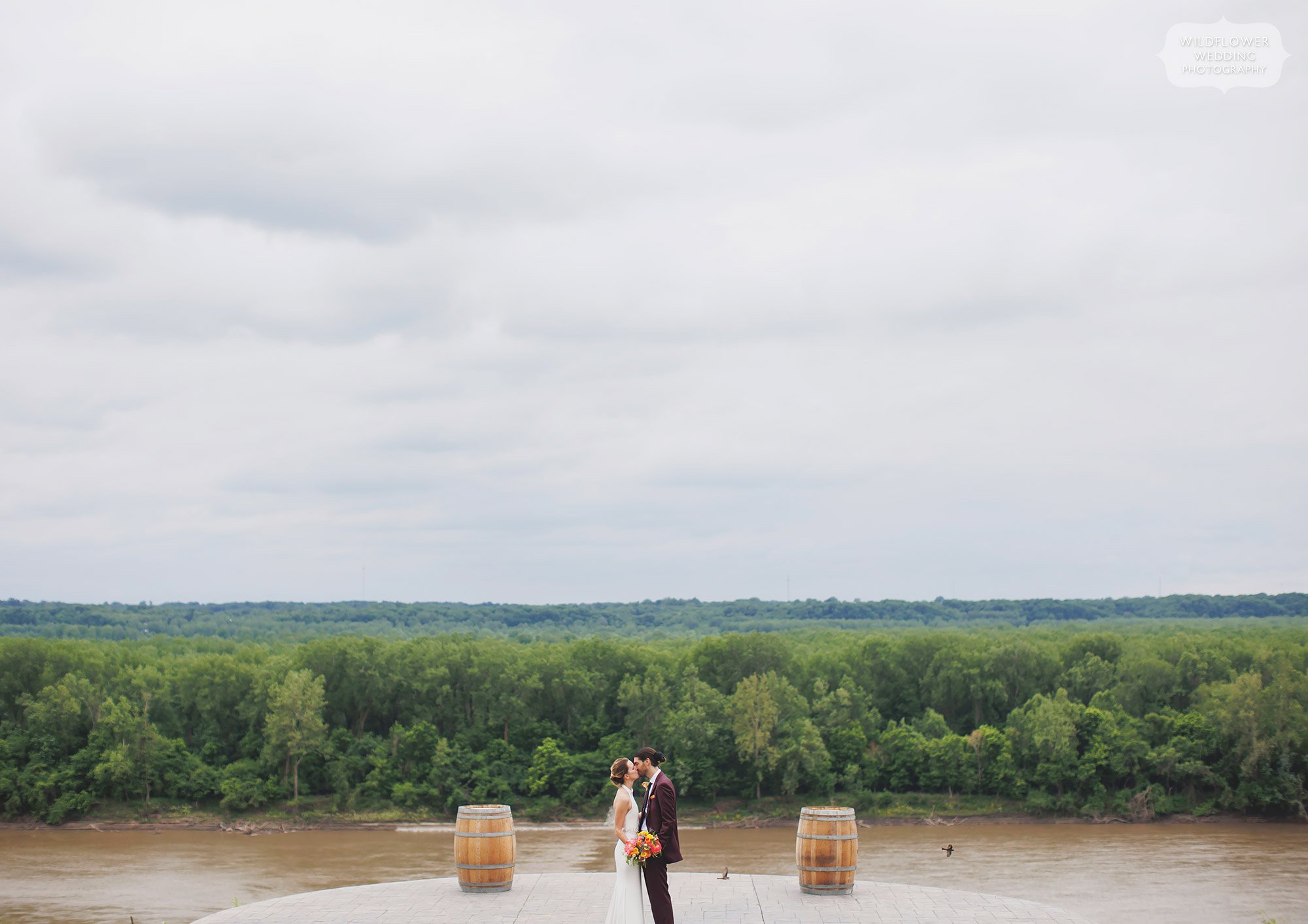 Bride and groom stand on bluff at Les Bourgeois Winery overlooking Missouri River.